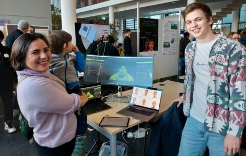 Smiling students in front of a computer screen.