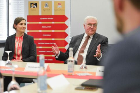 Anna Goldsworthy sits next to Federal President Steinmeier. Behind them are signs that read "Company Making", "Regulatory", "Financing" and "Internationalization".
